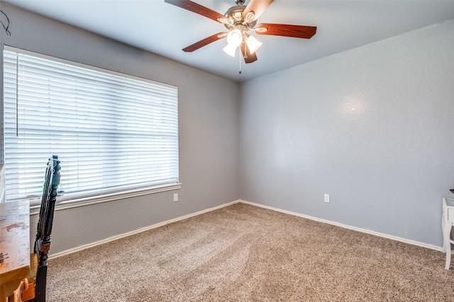 carpeted empty room featuring ceiling fan and baseboards
