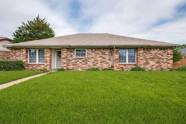 ranch-style house with a front yard, roof with shingles, and brick siding