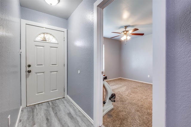 entrance foyer with ceiling fan, a textured wall, and baseboards