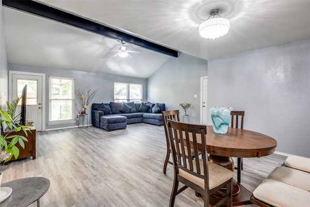 dining space with baseboards, lofted ceiling with beams, ceiling fan with notable chandelier, and light wood-style floors