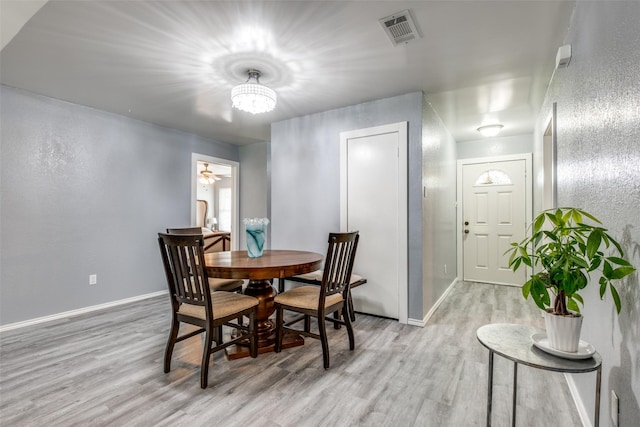 dining room featuring baseboards, visible vents, light wood-type flooring, and an inviting chandelier