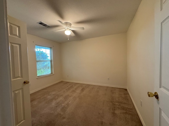 spare room with ceiling fan, carpet flooring, baseboards, visible vents, and a textured ceiling