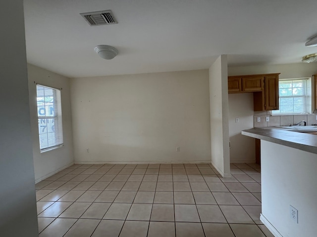 unfurnished dining area featuring light tile patterned floors, a sink, visible vents, and baseboards