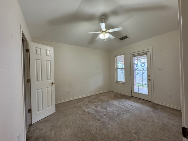 carpeted spare room featuring baseboards, visible vents, and ceiling fan