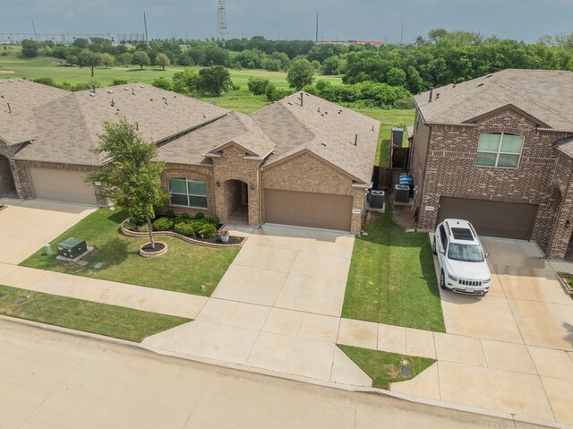 view of front of house with a shingled roof, brick siding, a front lawn, and concrete driveway