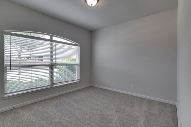 carpeted empty room featuring baseboards