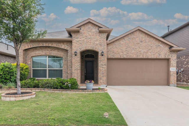 french country home with a front yard, an attached garage, and brick siding