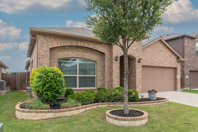view of front of property featuring driveway, fence, a front lawn, and brick siding