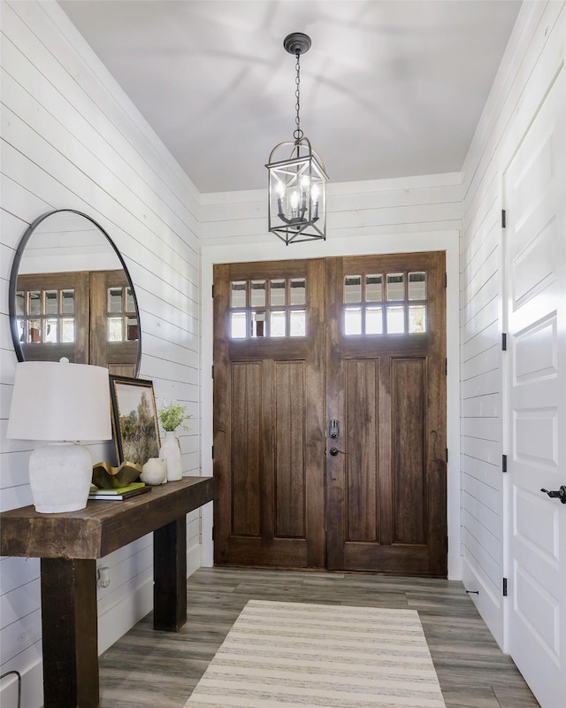 foyer with a notable chandelier, wood walls, and wood finished floors