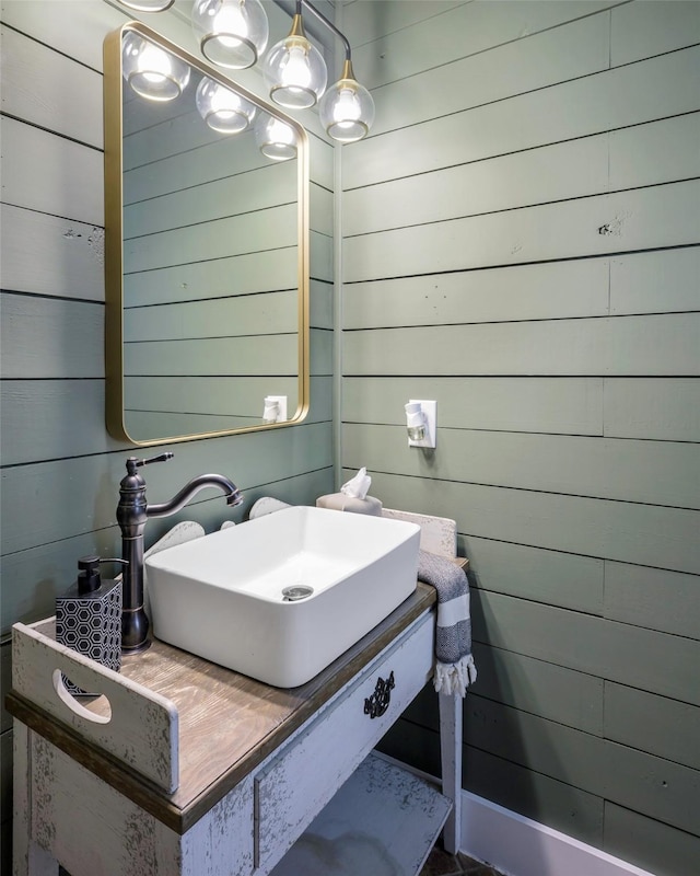bathroom featuring wood walls and a sink