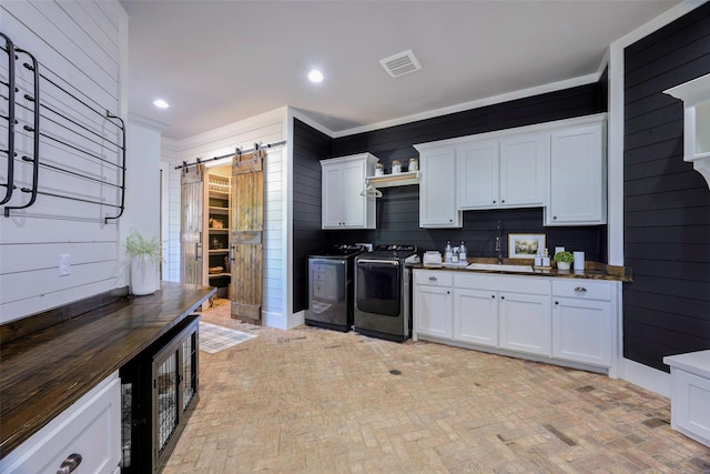 kitchen featuring dark countertops, a barn door, visible vents, washer and clothes dryer, and brick floor