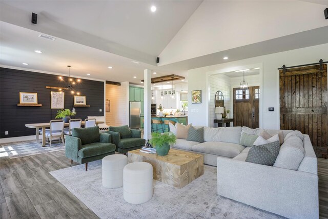 living area featuring wooden walls, a barn door, recessed lighting, and visible vents
