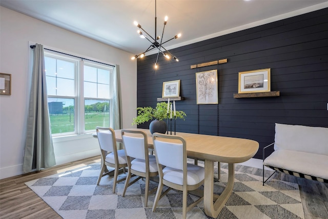 dining area with a chandelier, light wood finished floors, and baseboards