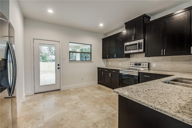 10169 Budtime Ln, Dallas, TX 75217 - kitchen with light stone counters, baseboards, tasteful backsplash, dark cabinetry, and stainless steel appliances