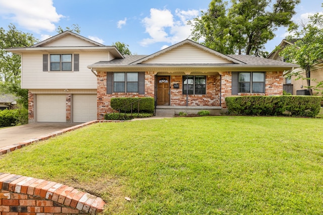 tri-level home featuring a garage, brick siding, a front yard, and driveway