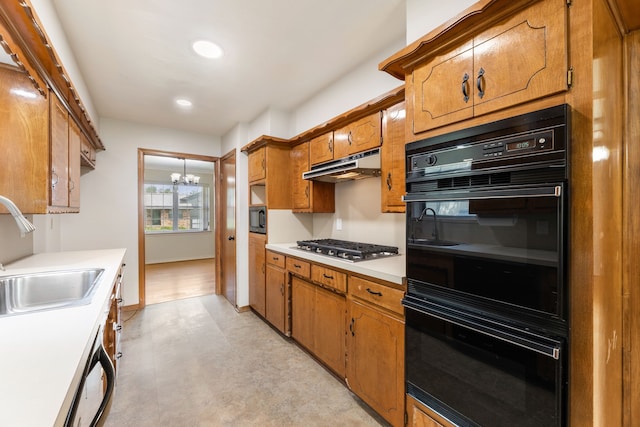 kitchen with a chandelier, brown cabinets, under cabinet range hood, and a sink