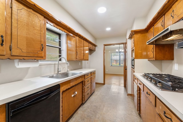 kitchen with a sink, appliances with stainless steel finishes, light countertops, under cabinet range hood, and brown cabinetry