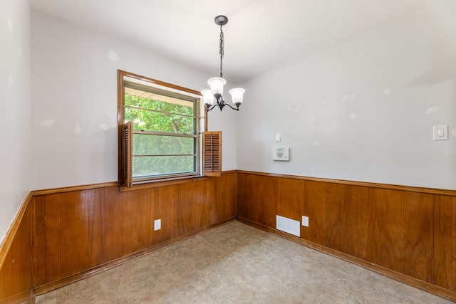 spare room featuring a chandelier, tile patterned floors, a wainscoted wall, visible vents, and wood walls