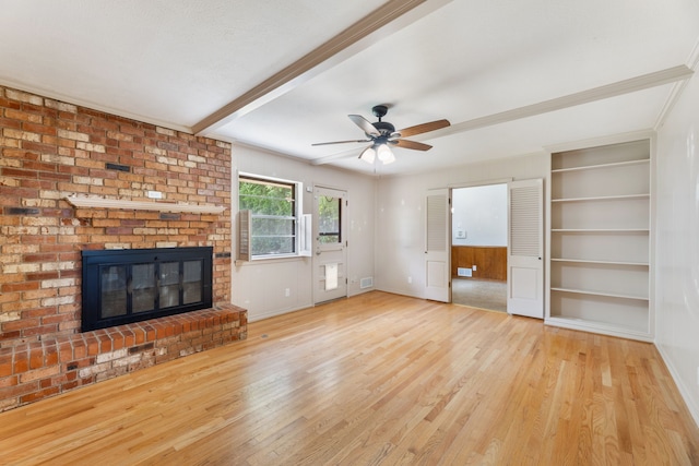 unfurnished living room with a fireplace, built in features, a ceiling fan, baseboards, and wood finished floors