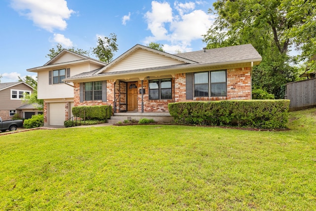 split level home featuring a front yard, a garage, a shingled roof, brick siding, and fence