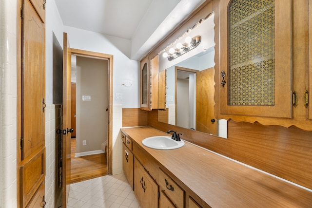 bathroom with tile patterned flooring, a wainscoted wall, tile walls, and vanity