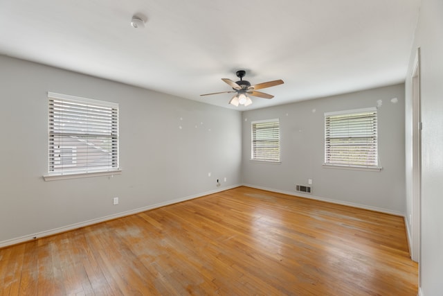 spare room featuring light wood finished floors, visible vents, ceiling fan, and baseboards