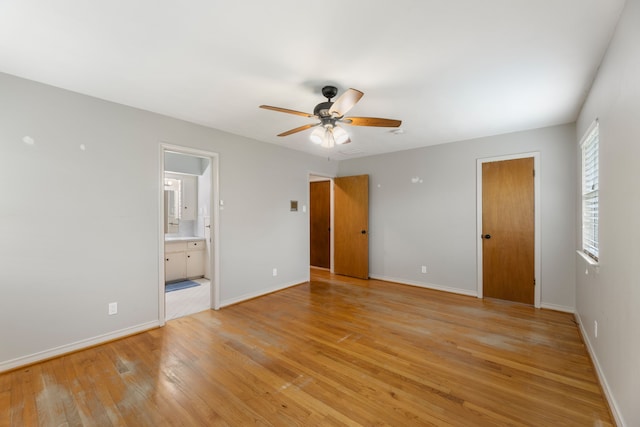 unfurnished bedroom with light wood-type flooring, a ceiling fan, ensuite bathroom, and baseboards