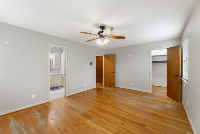 unfurnished bedroom with baseboards, a spacious closet, and light wood-type flooring