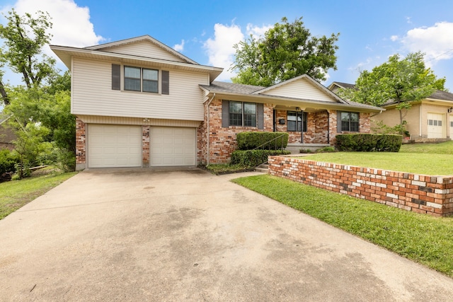 split level home featuring driveway, a front yard, brick siding, and a garage