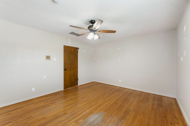 empty room with light wood-style floors, visible vents, a ceiling fan, and baseboards