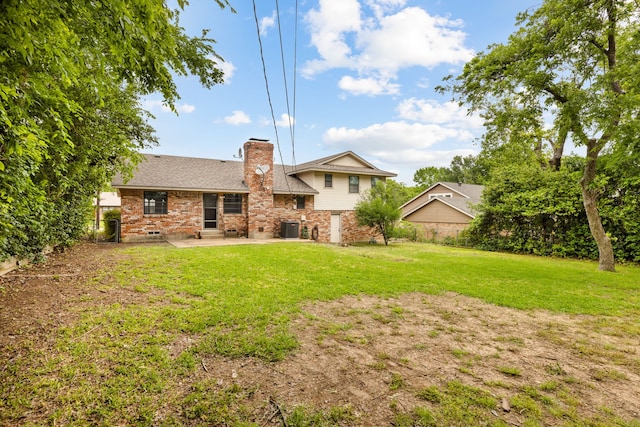 rear view of property with a patio, brick siding, a yard, central AC, and a chimney