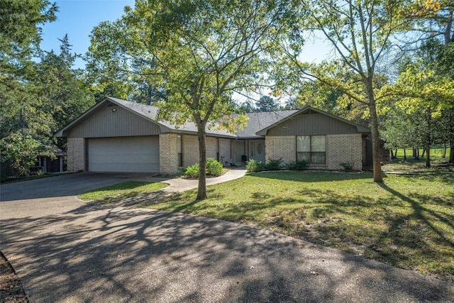 ranch-style home with a front yard, concrete driveway, a garage, and brick siding
