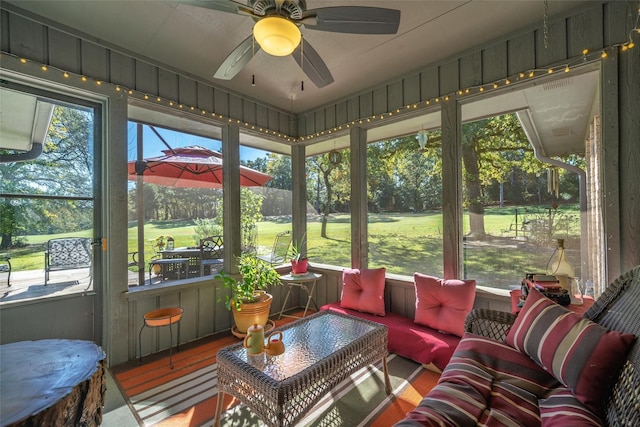 sunroom with golf course view, a ceiling fan, and an outdoor hangout area