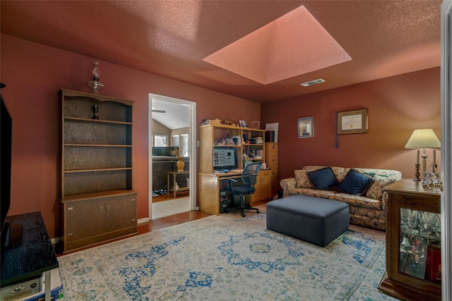 home office with a textured ceiling, visible vents, baseboards, and a skylight