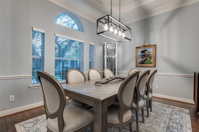 dining space with baseboards, wood finished floors, crown molding, and a tray ceiling