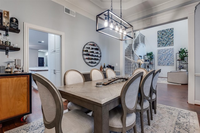 dining space with visible vents, an inviting chandelier, ornamental molding, wood finished floors, and stairs