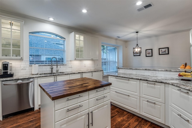 kitchen with stainless steel dishwasher, butcher block counters, ornamental molding, a sink, and visible vents