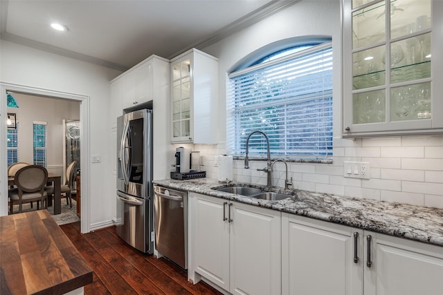 kitchen with stainless steel appliances, crown molding, backsplash, a sink, and dark wood-type flooring
