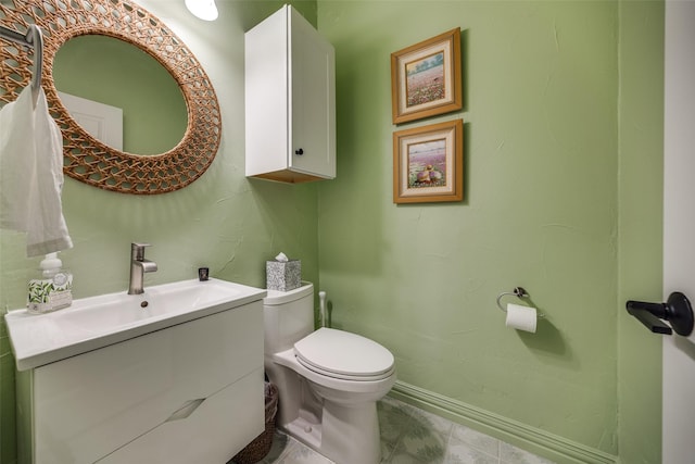 bathroom with toilet, vanity, and baseboards
