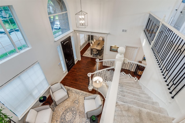 entrance foyer with a chandelier, visible vents, wood finished floors, and a high ceiling