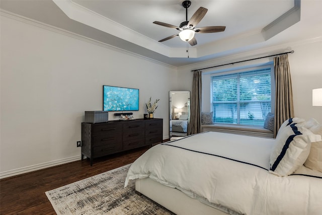 bedroom with dark wood-style floors, a raised ceiling, a ceiling fan, baseboards, and ornamental molding