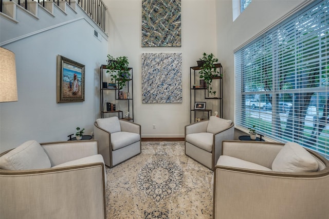 living area featuring a high ceiling, baseboards, and plenty of natural light