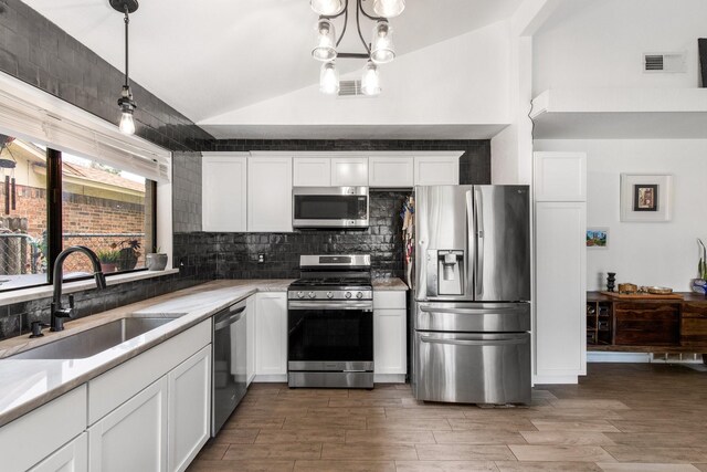 2409 Leslie St, Denton, TX 76205 - kitchen with backsplash, a sink, white cabinets, lofted ceiling, and stainless steel appliances