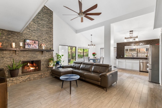 2409 Leslie St, Denton, TX 76205 - living area with light wood-style floors, ceiling fan with notable chandelier, a fireplace, and high vaulted ceiling