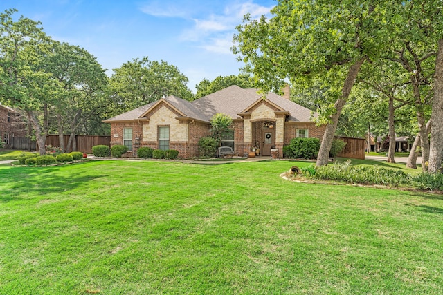 single story home featuring a chimney, a front yard, a shingled roof, and brick siding