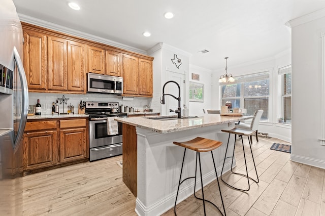 kitchen featuring an inviting chandelier, stainless steel appliances, ornamental molding, and brown cabinetry