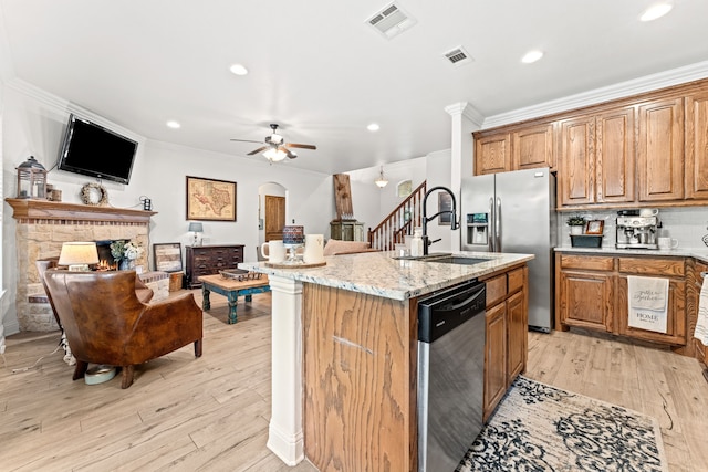 kitchen with light stone countertops, stainless steel appliances, light wood-style floors, a sink, and visible vents