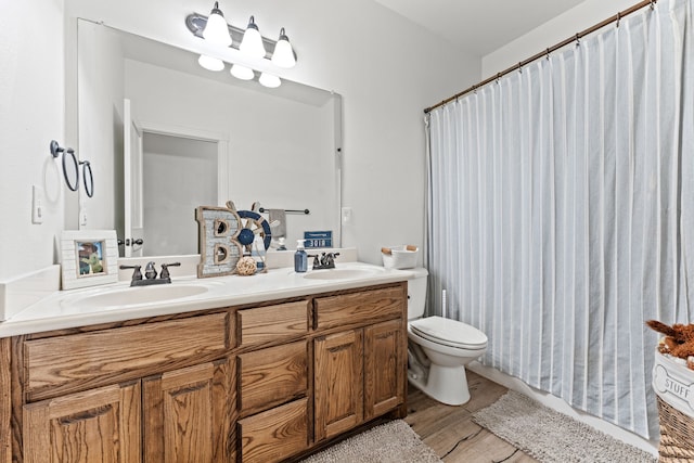full bathroom with double vanity, wood finished floors, toilet, and a sink