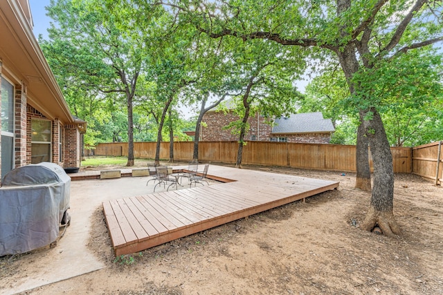 deck with area for grilling, a patio area, and a fenced backyard
