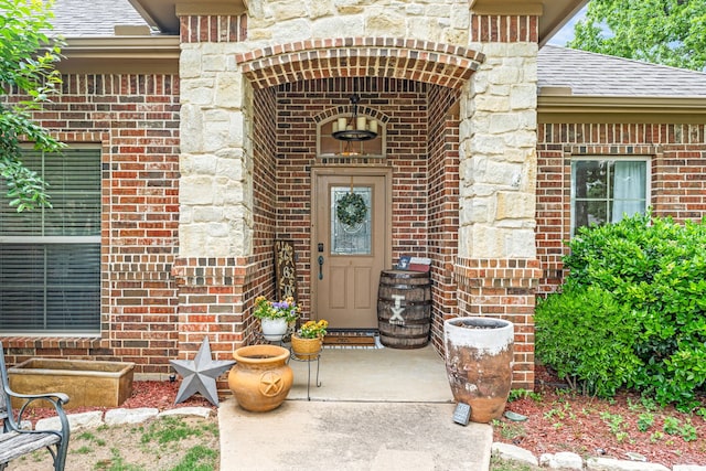 property entrance featuring stone siding, brick siding, and roof with shingles